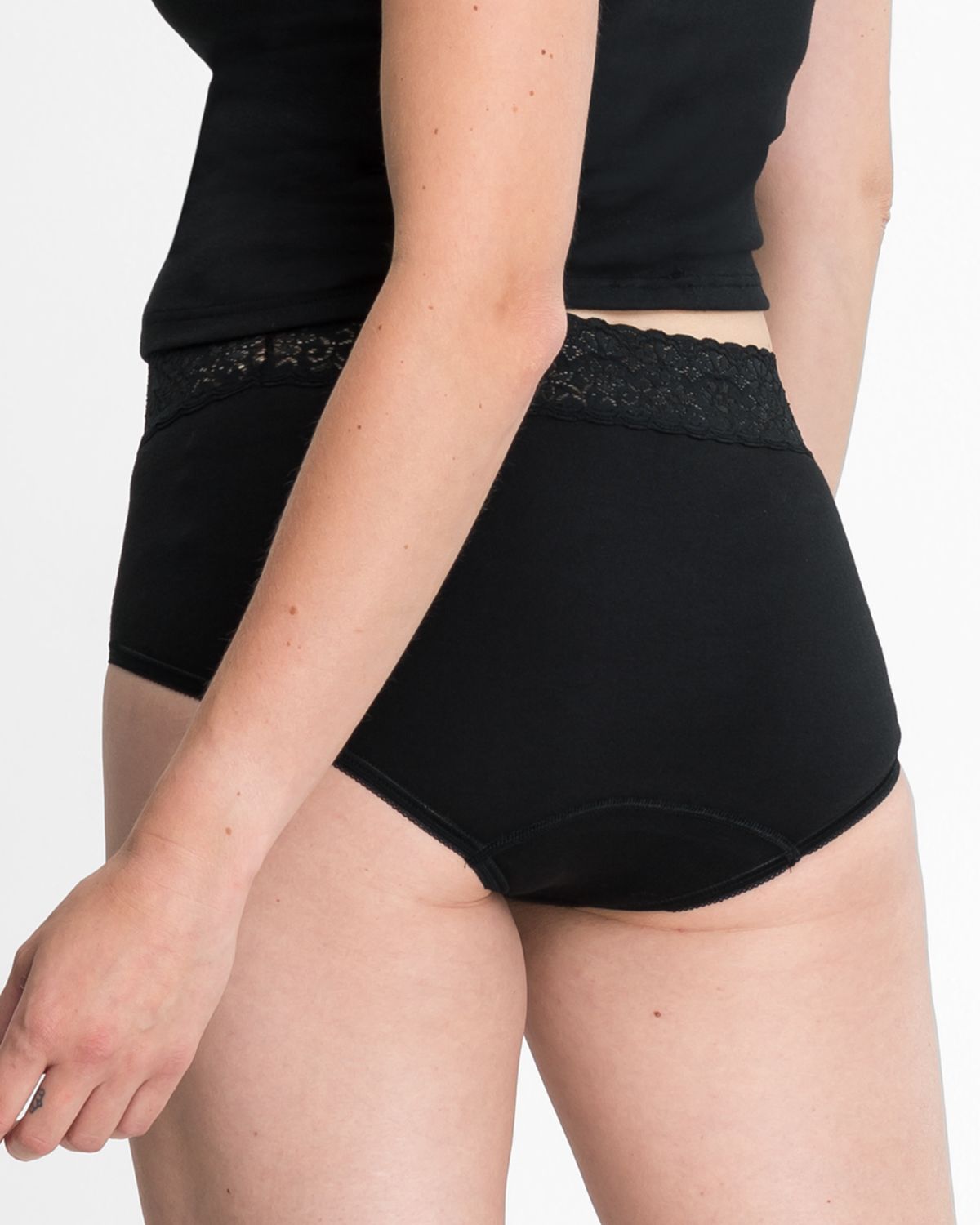 Model trägt Taillenslip in schwarz aus der Serie Natalie, Ansicht von hinten.