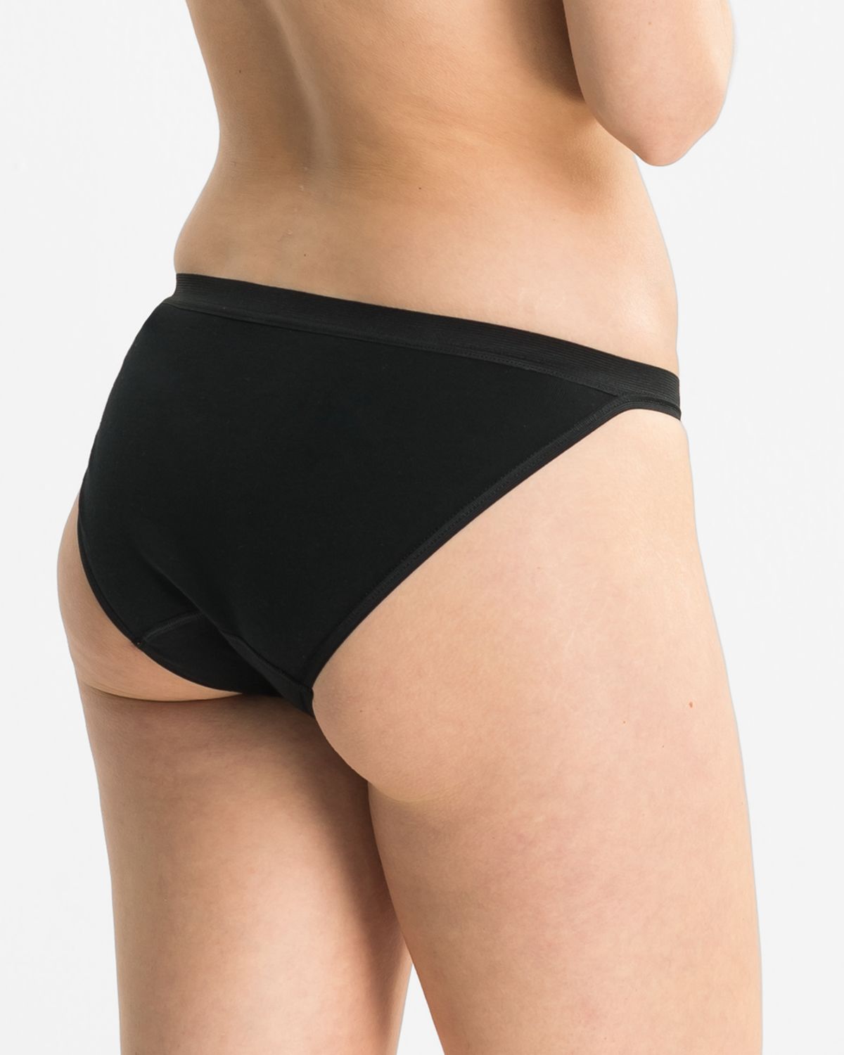 Model trägt Tanga in schwarz aus der Serie Britta, Ansicht von hinten.