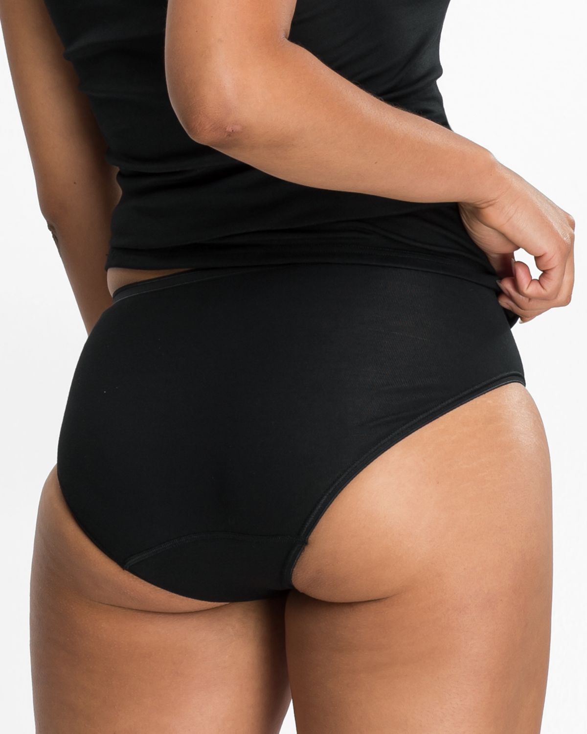 Model trägt Hüftslip in schwarz aus der Serie Nadine, Ansicht von hinten.