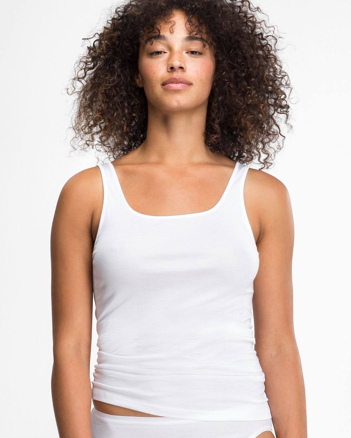 Model trägt Achselhemd in weiß aus der Serie Nadine, Ansicht von vorne.