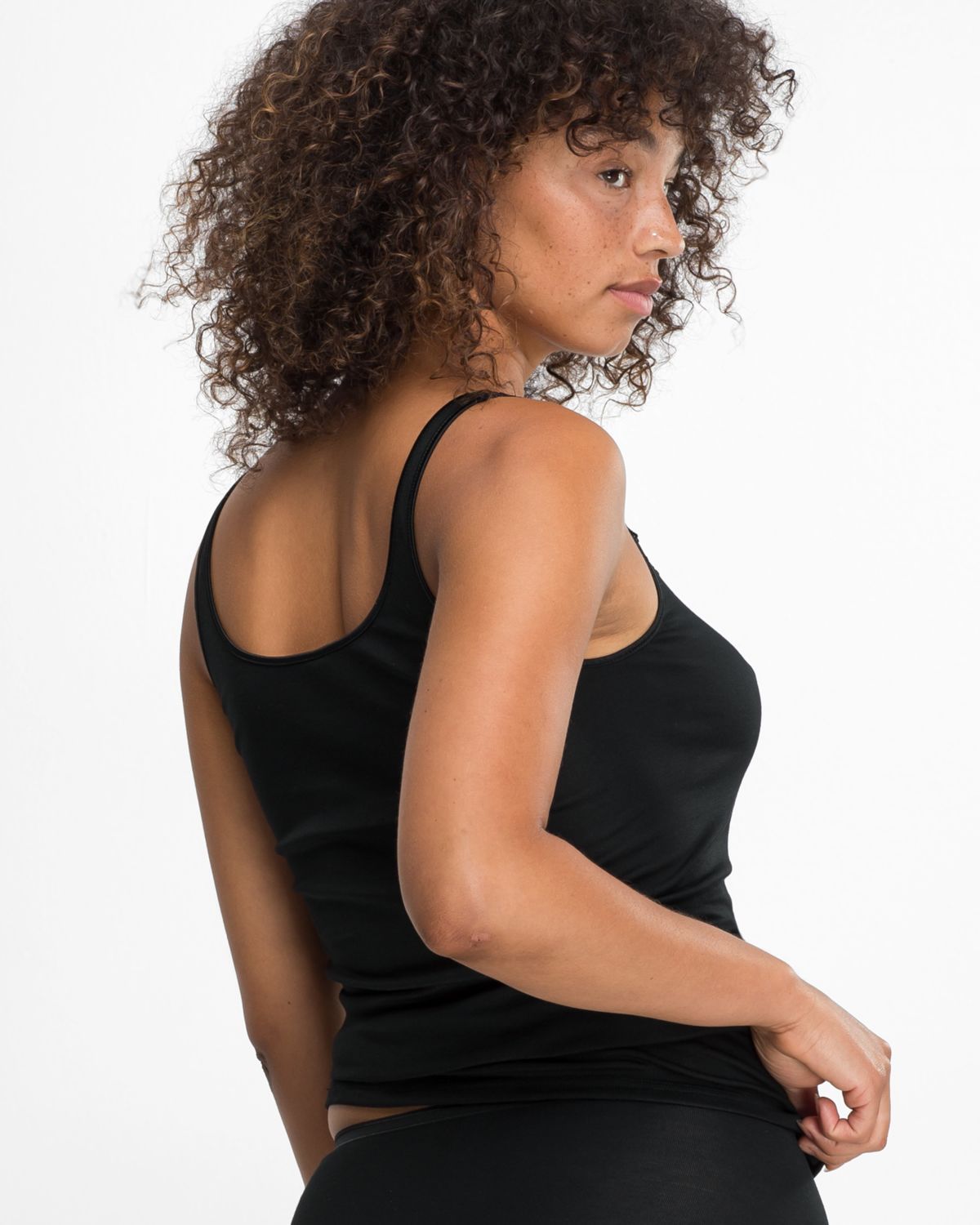 Model trägt Trägerhemd in schwarz aus der Serie Nadine, Ansicht von hinten.