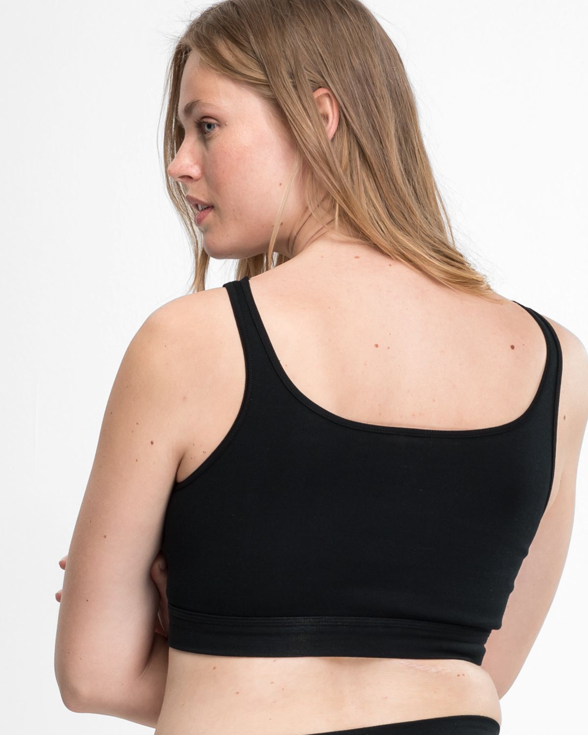 Model trägt Trägerbustier in schwarz aus der Serie Bio Cotton, Ansicht von hinten.