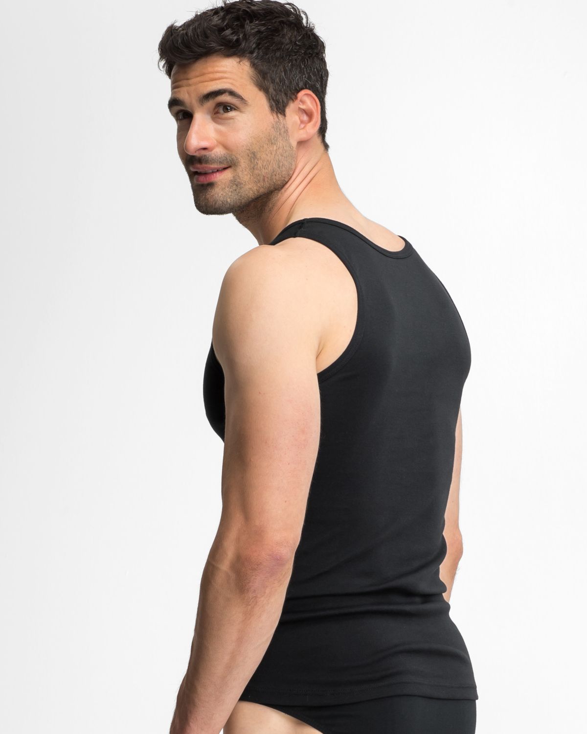 Model trägt Herren Achselhemd in schwarz aus der Serie Classic, Ansicht von hinten.