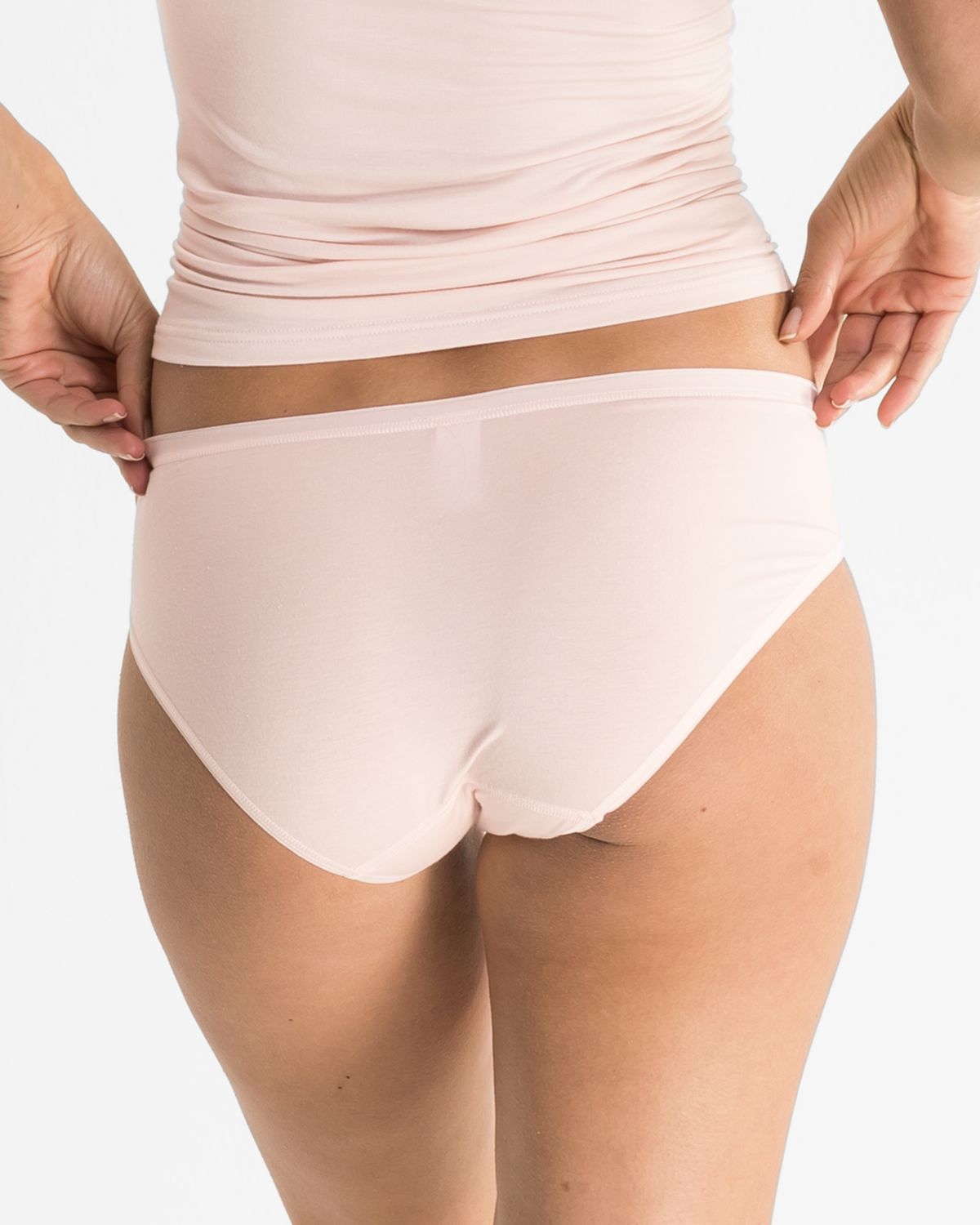 Model trägt Minislip in lychee aus der Serie Sensuelle, Ansicht von hinten.