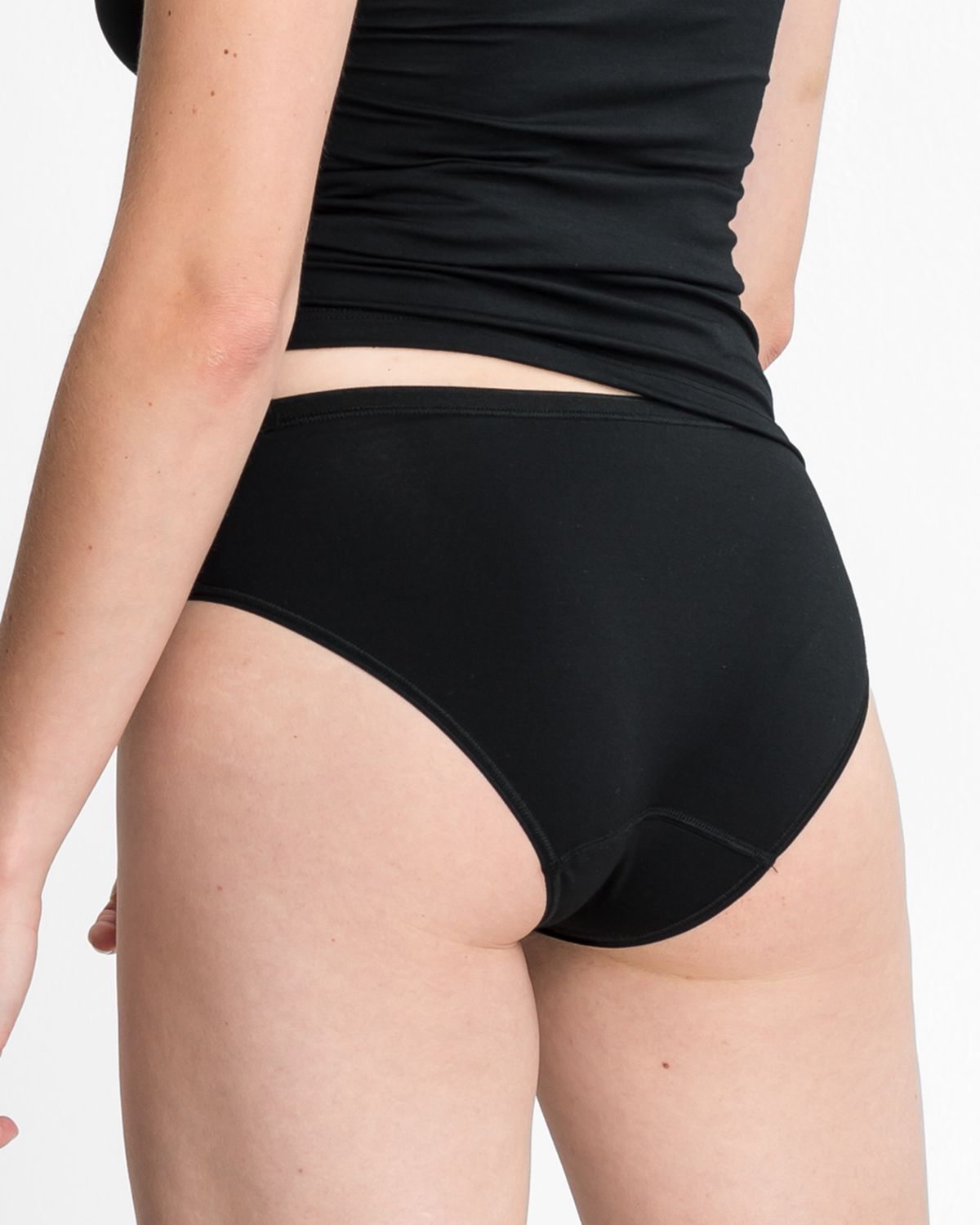 Model trägt Minislip in schwarz aus der Serie Sensuelle, Ansicht von hinten.