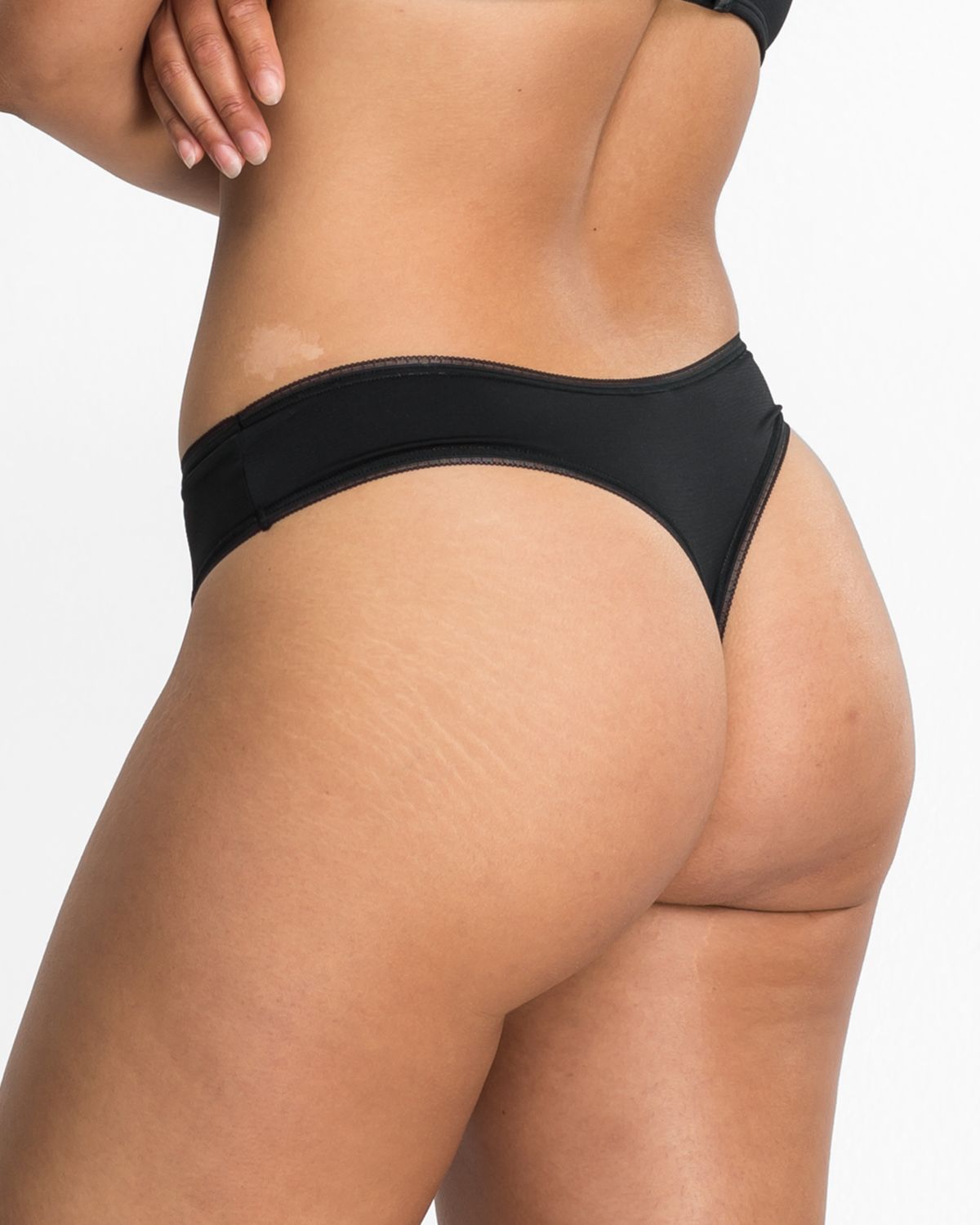 Model trägt String Tanga in schwarz aus der Serie Magic look, Ansicht von hinten.
