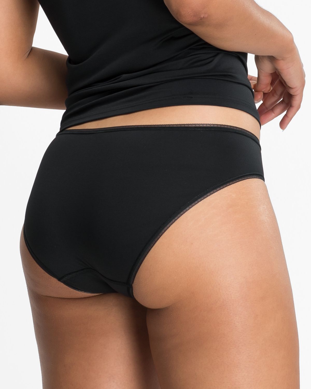 Model trägt Minislip in schwarz aus der Serie Magic look, Ansicht von hinten.