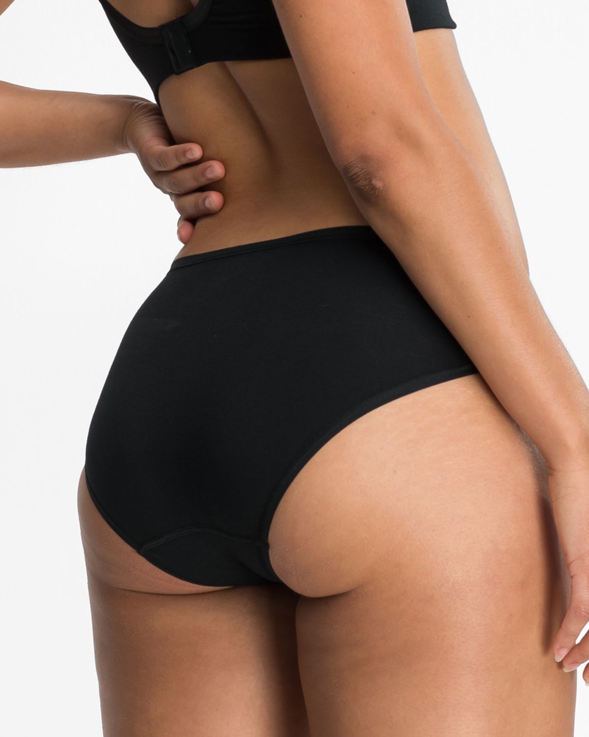 Model trägt Bikinislip in schwarz aus der Serie Natural Beauty, Ansicht von hinten.