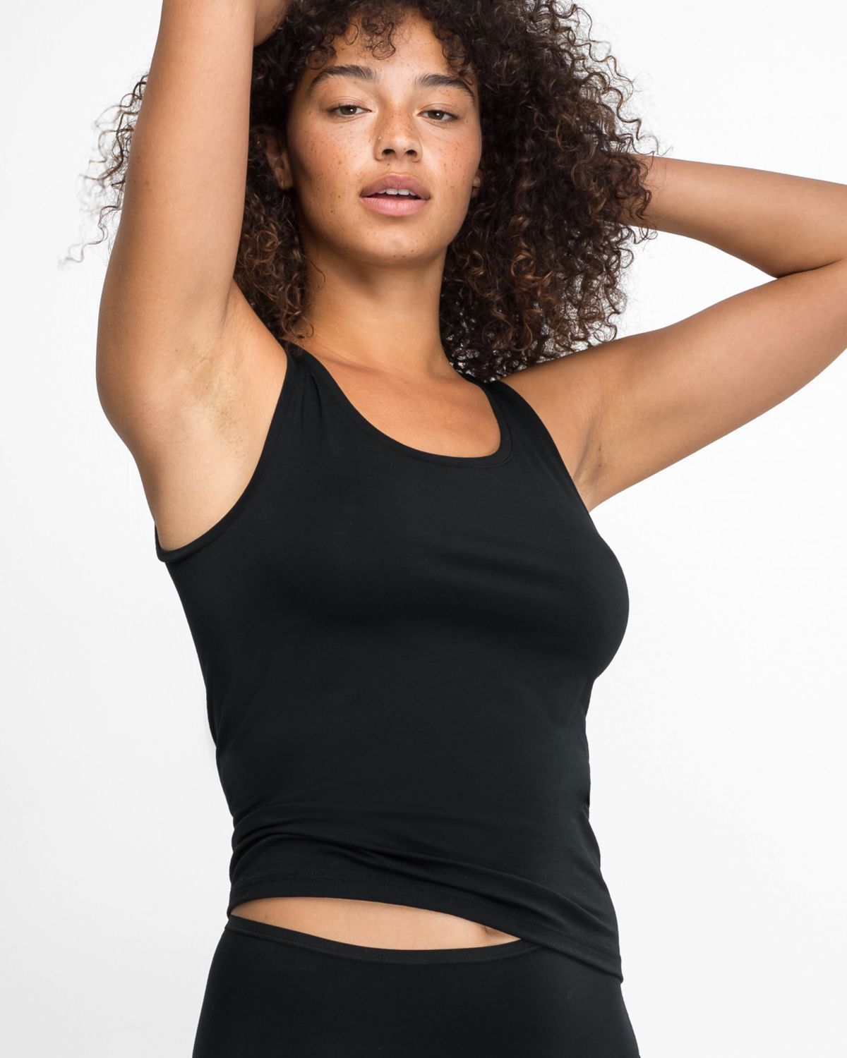 Model trägt Achseltop in schwarz aus der Serie Natural Beauty, Ansicht von vorne.