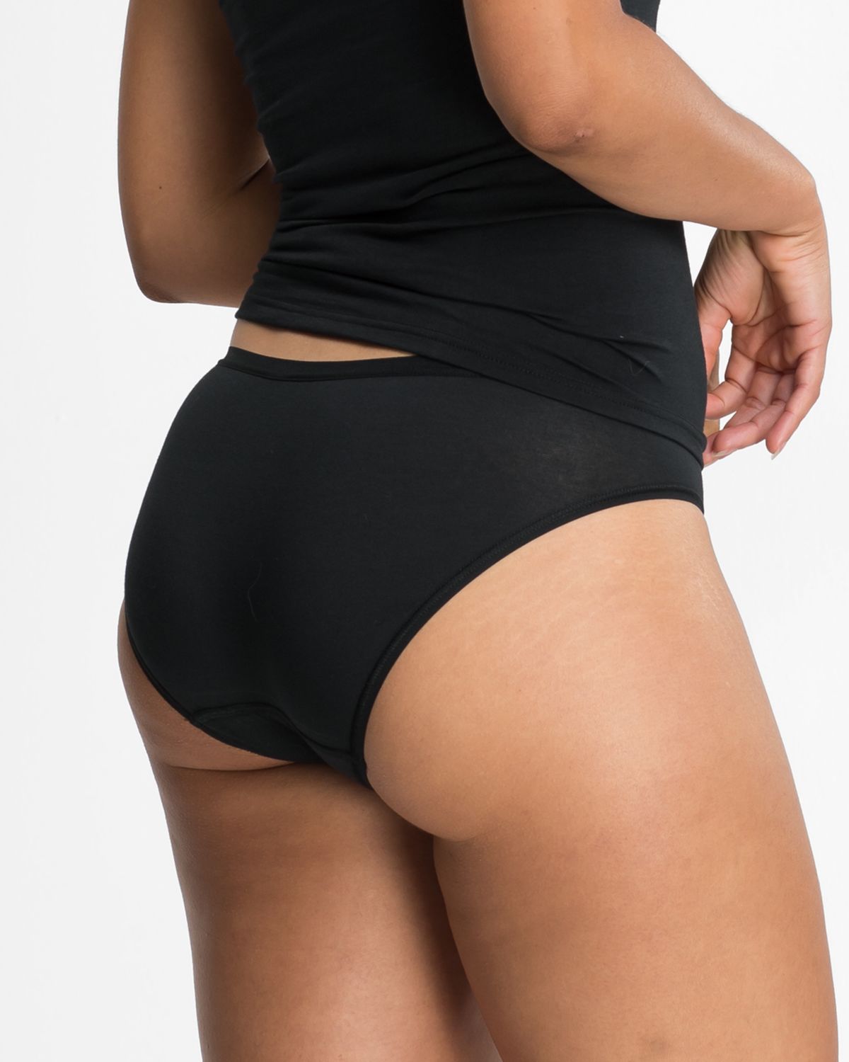 Model trägt Minislip in schwarz aus der Serie Take two, Ansicht von hinten.