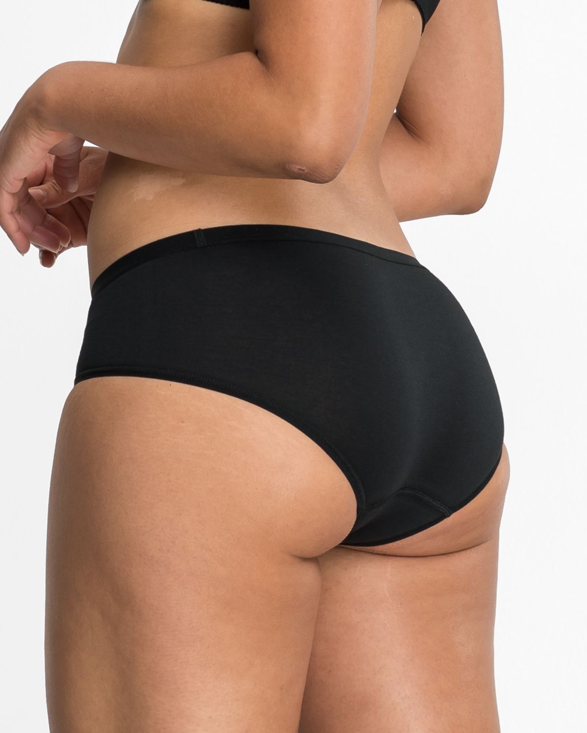 Model trägt Low Hip in schwarz aus der Serie Take two, Ansicht von hinten.