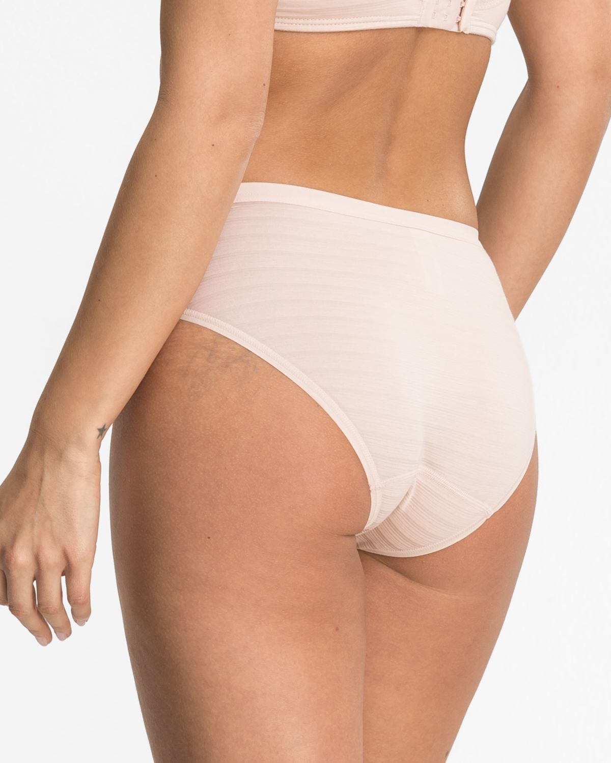 Model trägt Bikinislip in honey aus der Serie Cotton&More, Ansicht von hinten.