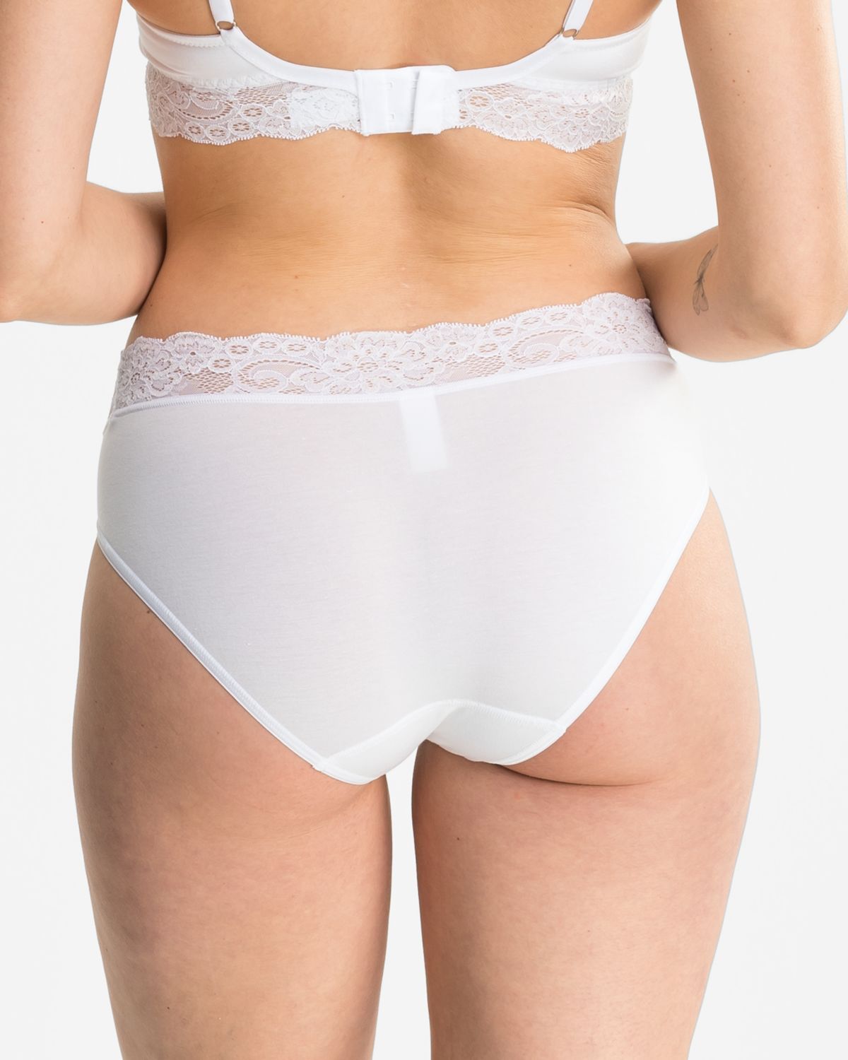 Model trägt Bikinislip in weiß aus der Serie Sensuelle Lace, Ansicht von hinten.