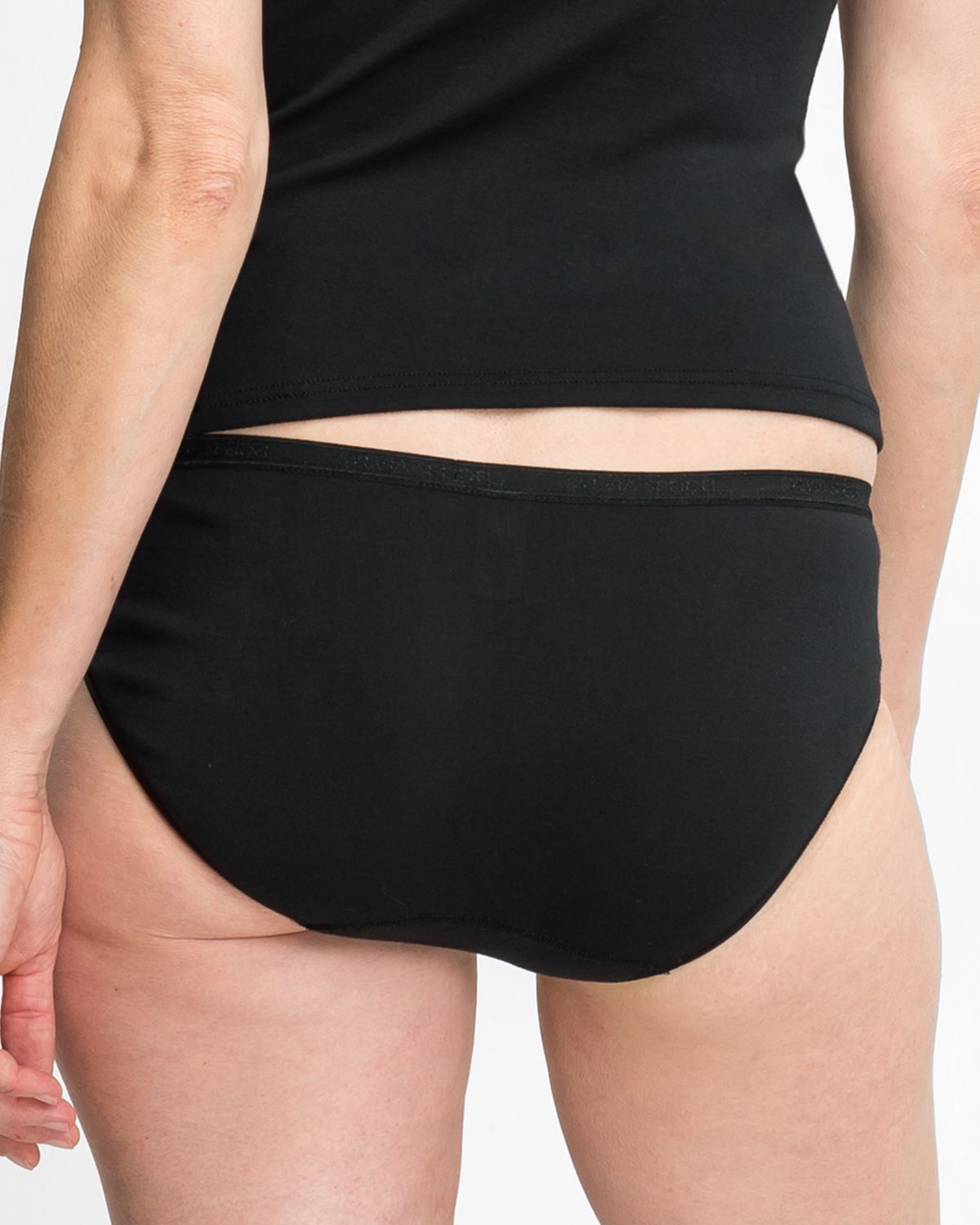 Model trägt Minislip in schwarz aus der Serie Silke, Ansicht von hinten.