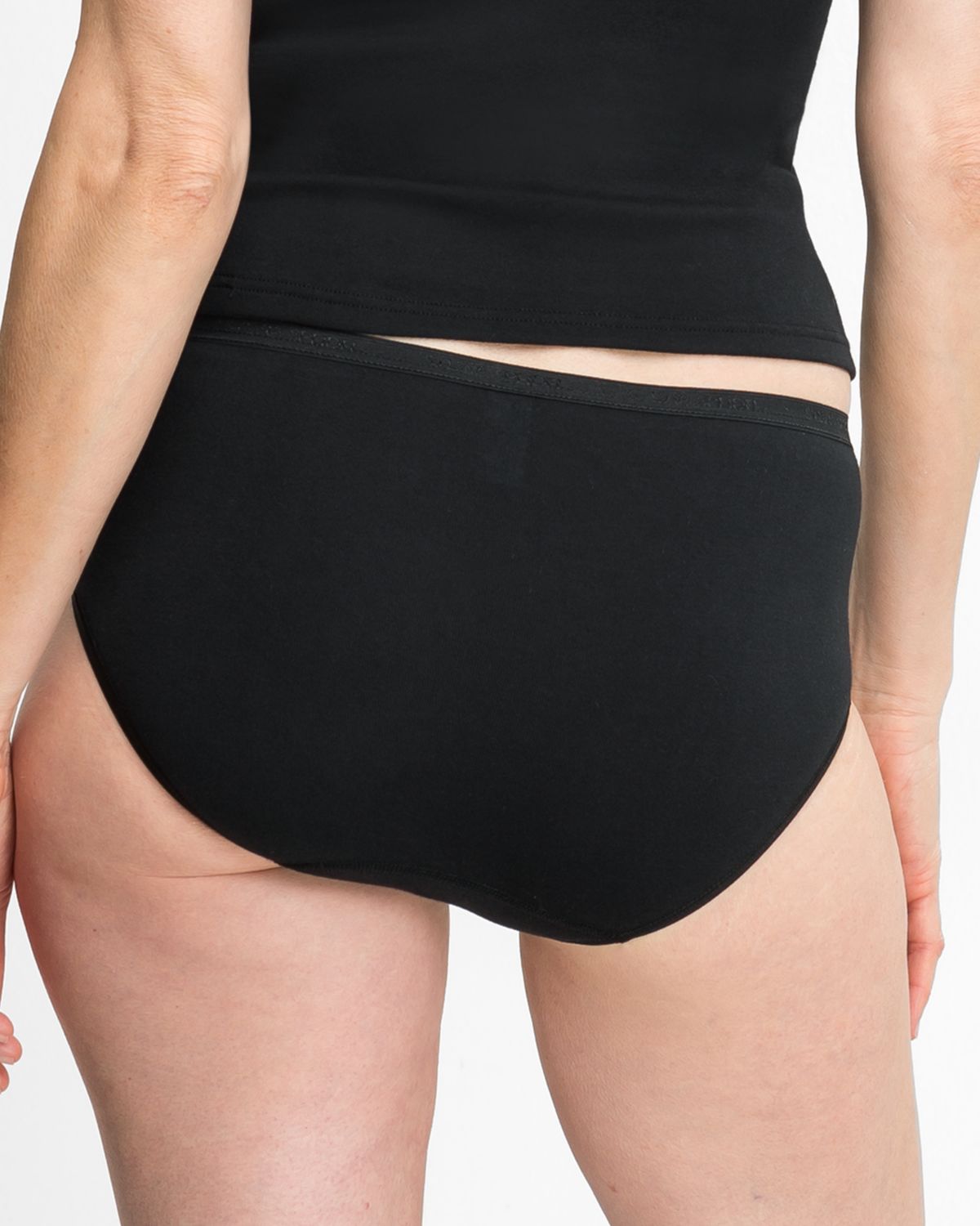 Model trägt Maxislip in schwarz aus der Serie Silke, Ansicht von hinten.