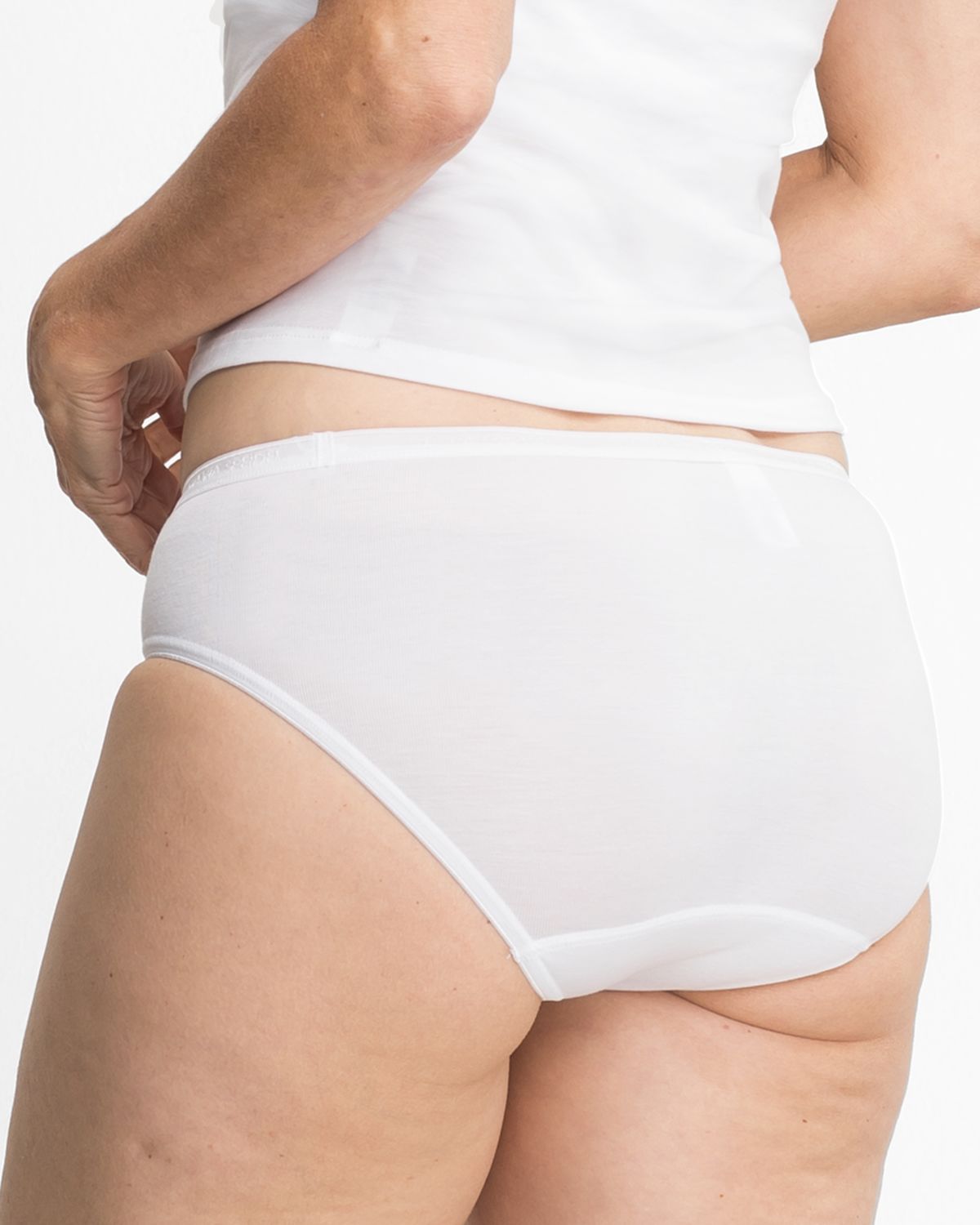 Model trägt Hüftslip in weiß aus der Serie Sofia, Ansicht von hinten.