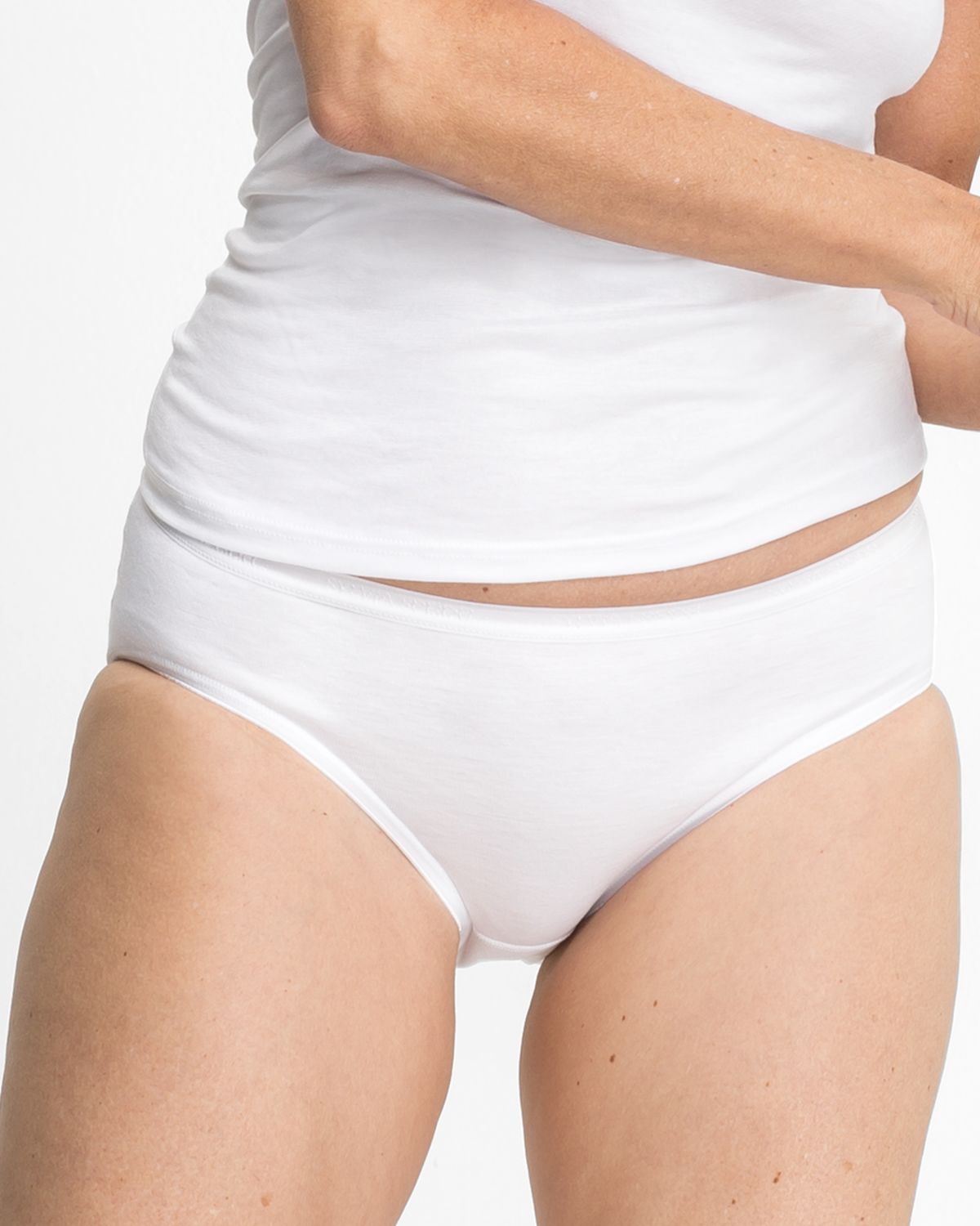 Model trägt Hüftslip in weiß aus der Serie Sofia, Ansicht von vorne.