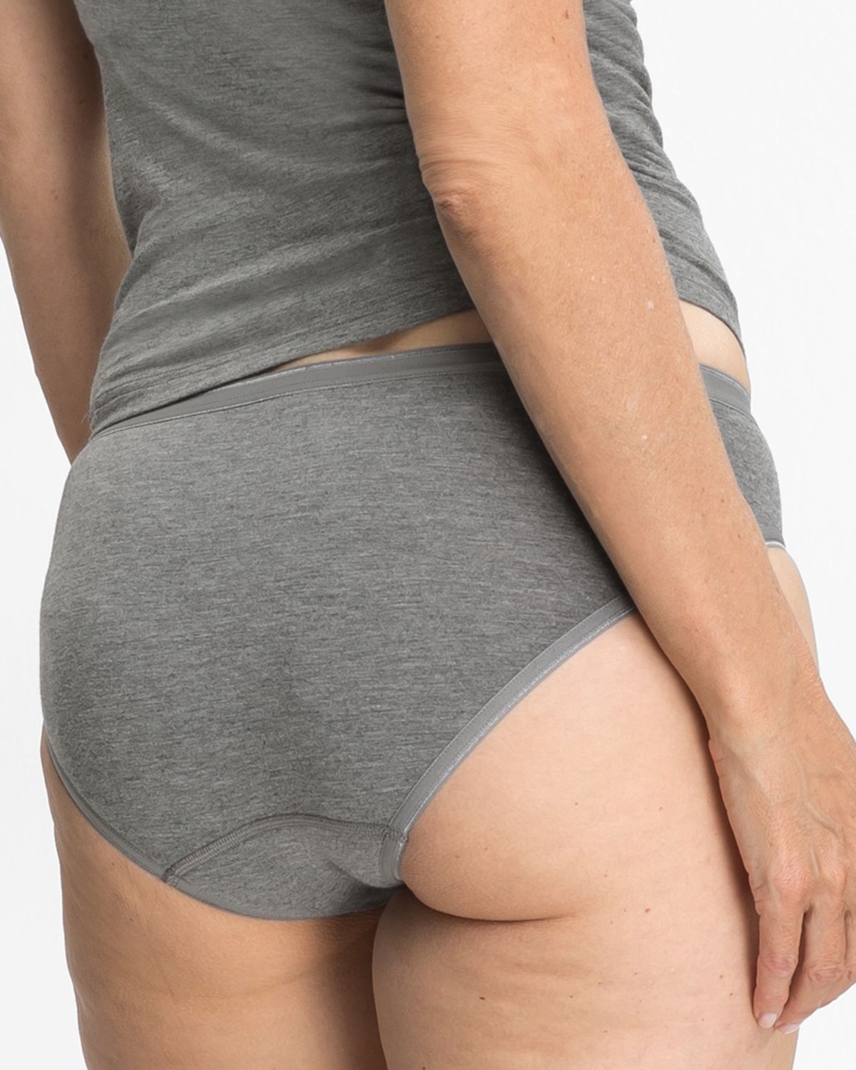 Model trägt Minislip in grau mélé aus der Serie Swenja, Ansicht von hinten.