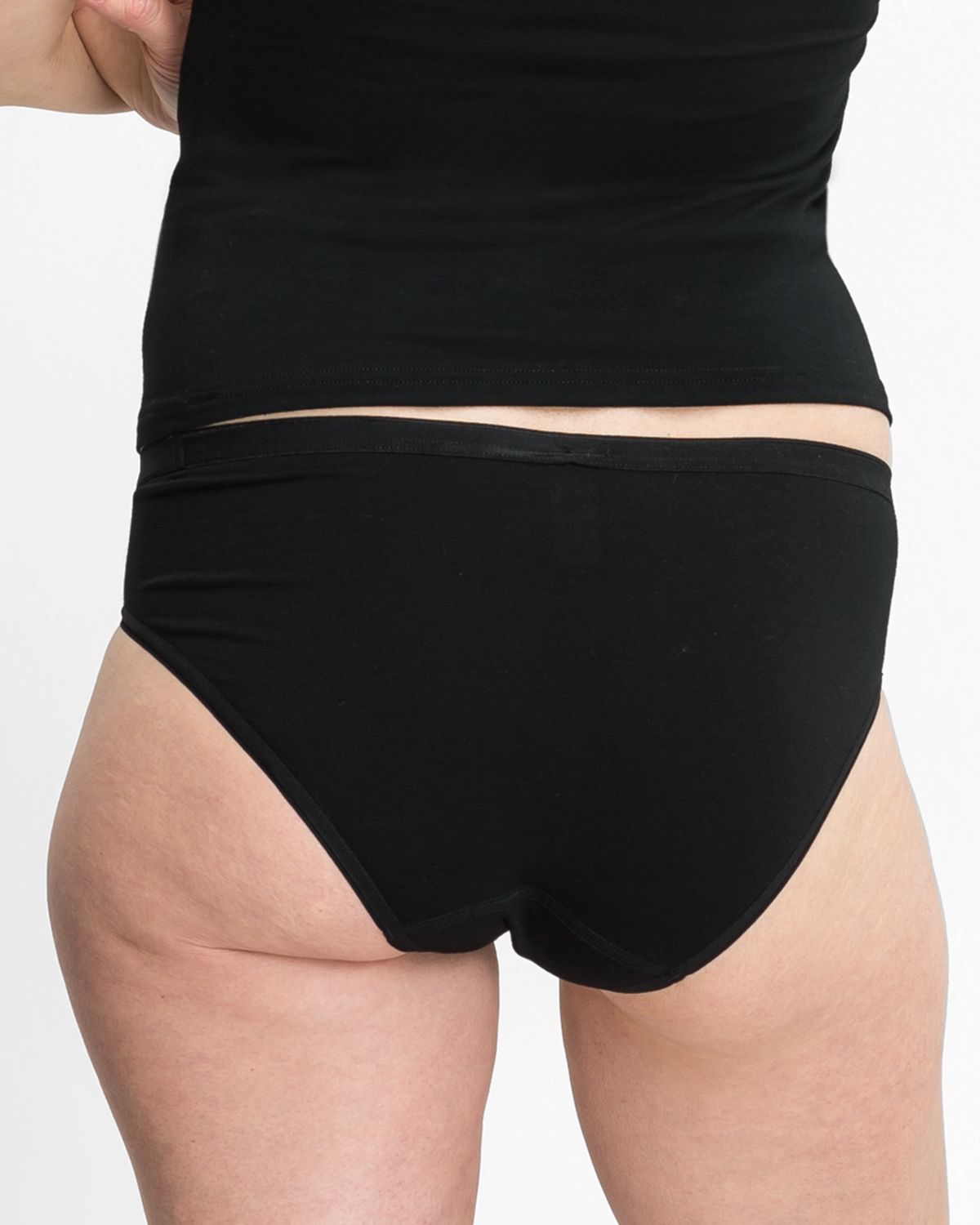 Model trägt Minislip in schwarz aus der Serie Swenja, Ansicht von hinten.