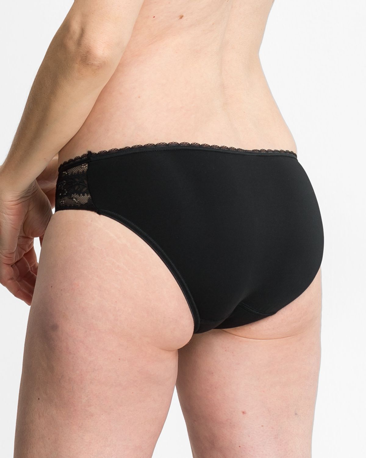 Model trägt Bikinislip in schwarz aus der Serie Silvana, Ansicht von hinten.