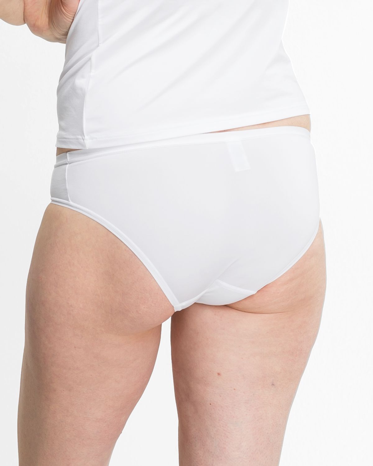 Model trägt Bikinislip in weiß aus der Serie Sidney, Ansicht von hinten.