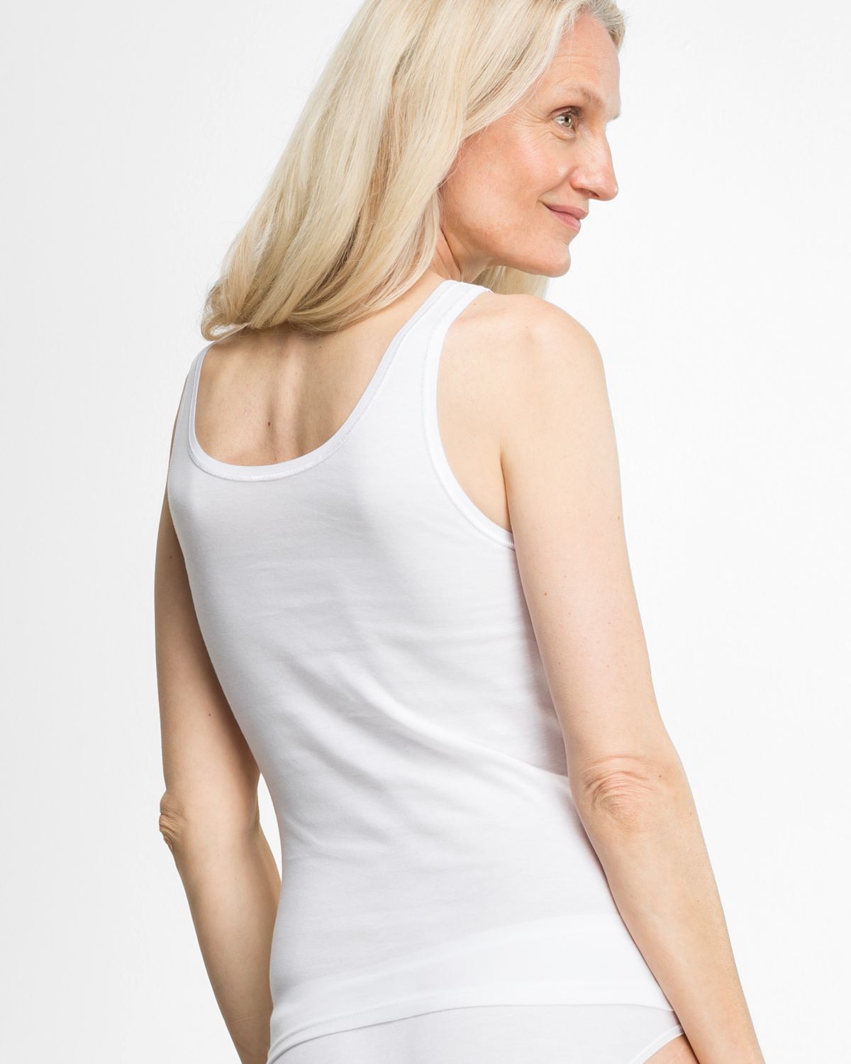 Model trägt Achselhemd in weiß aus der Serie Silke, Ansicht von hinten.