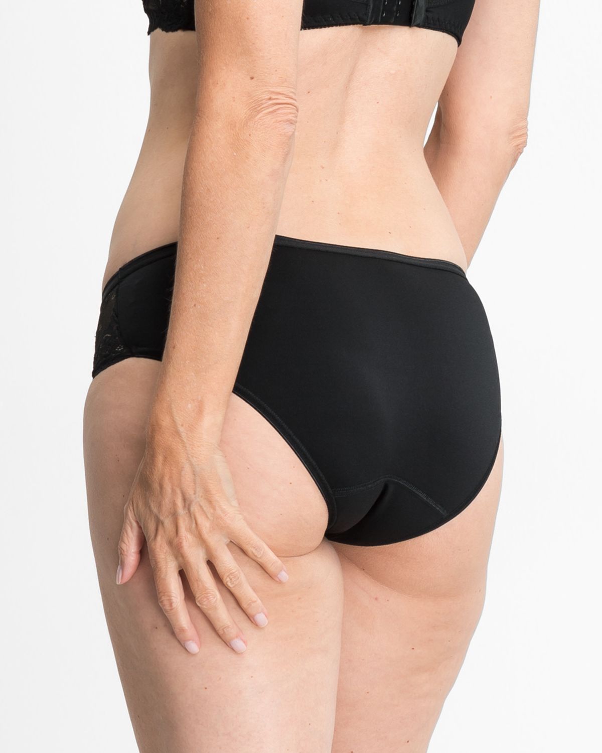 Model trägt Bikinislip in schwarz aus der Serie Severine, Ansicht von hinten.