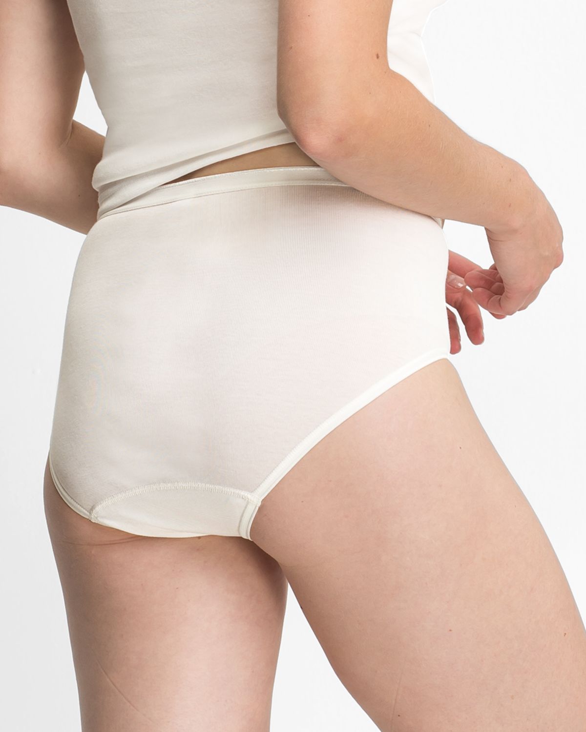 Model trägt Taillenslip in elfenbein aus der Serie Nele, Ansicht von hinten.