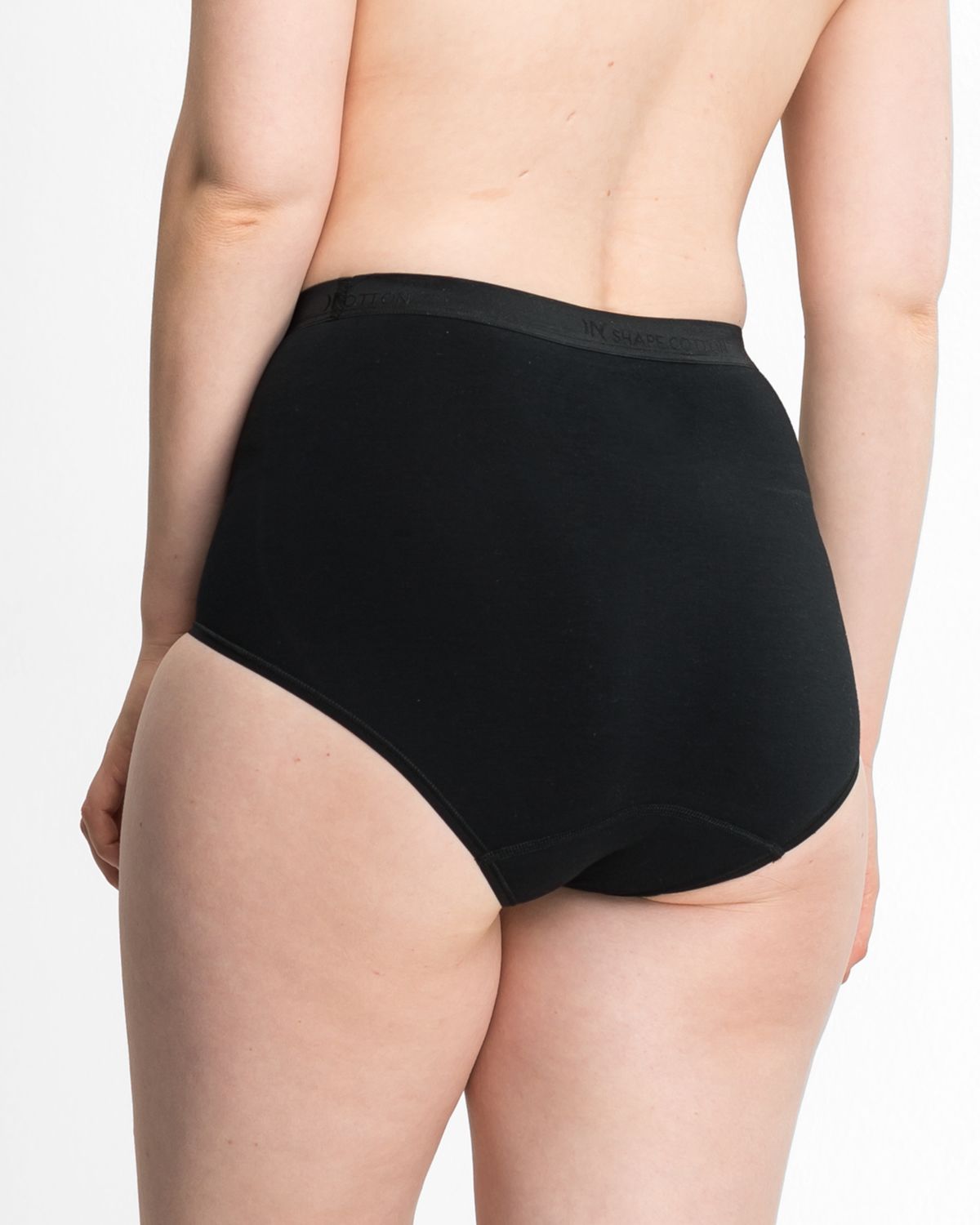 Model trägt High Waist Slip in schwarz aus der Serie Inshape Cotton, Ansicht von hinten.
