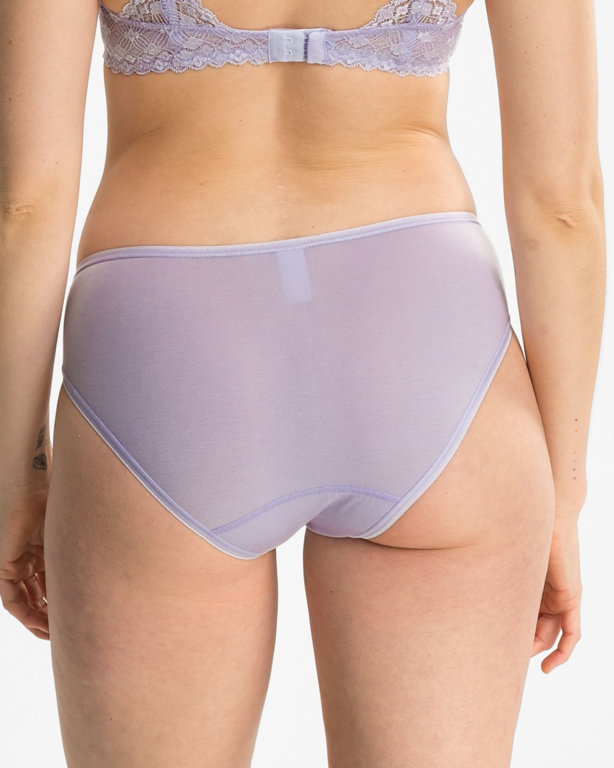 Model trägt Bikinislip in lavendel aus der Serie Romina, Ansicht von hinten.