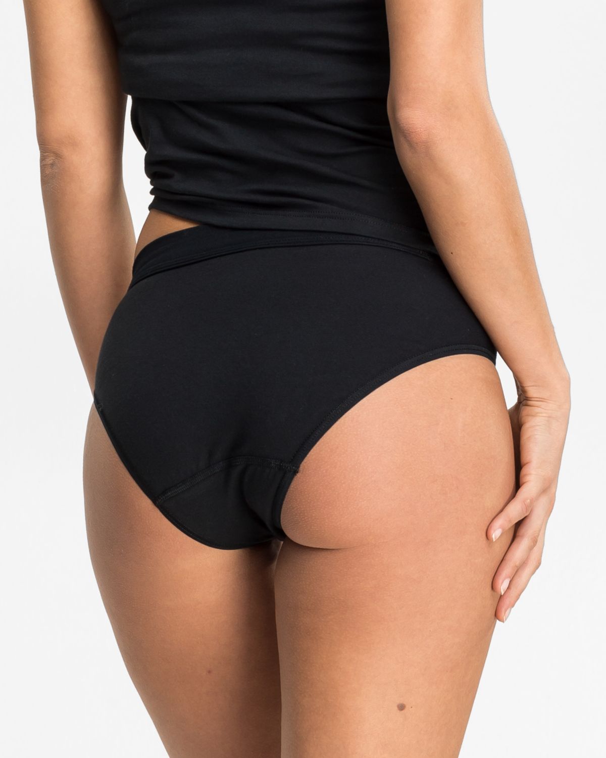 Model trägt Bikinislip in schwarz aus der Serie Cotton Sport, Ansicht von hinten.