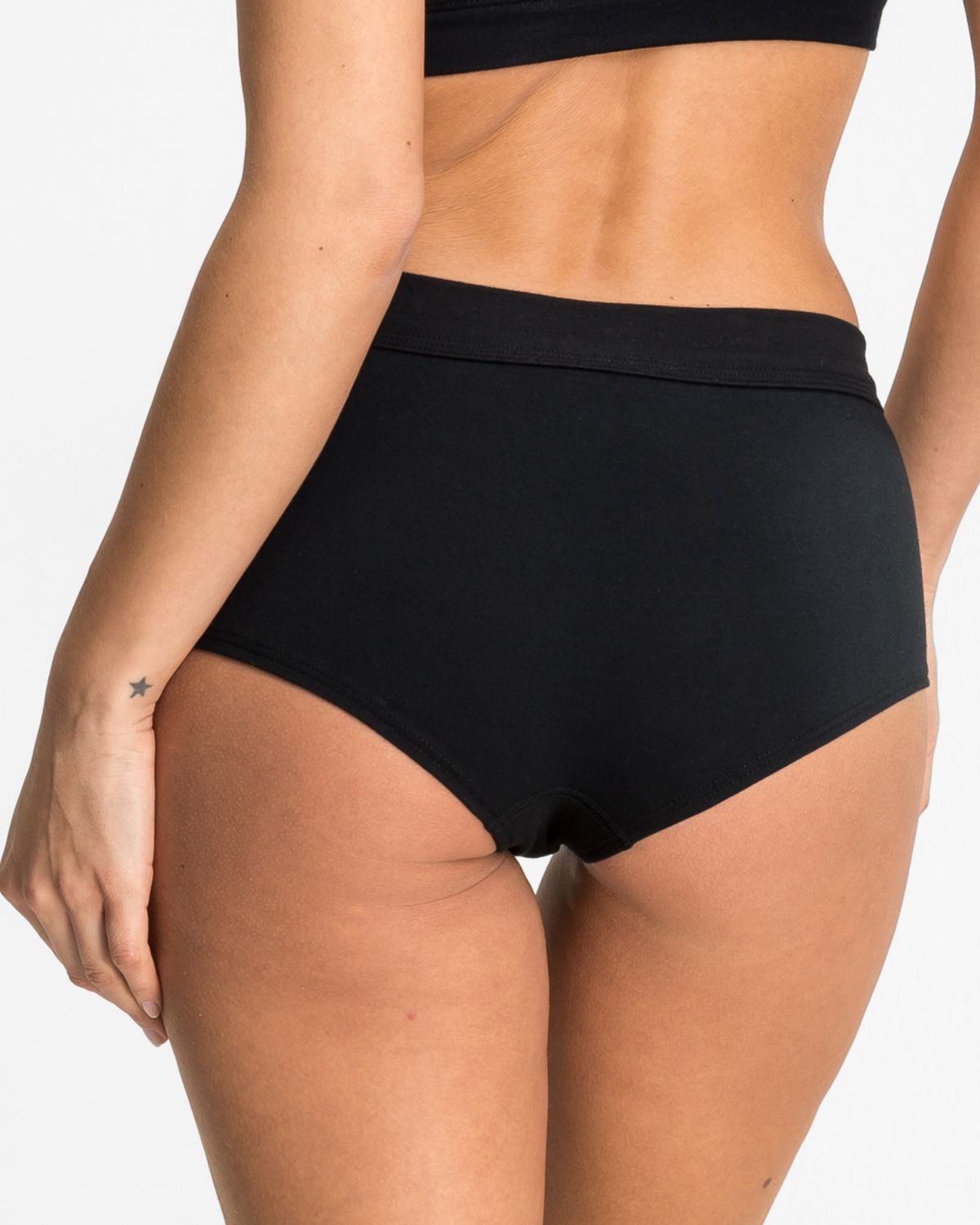 Model trägt Pant in schwarz aus der Serie Cotton Sport, Ansicht von hinten.