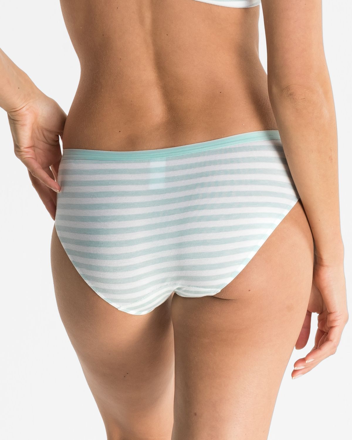 Model trägt Bikinislip in minze / off white aus der Serie Regina, Ansicht von hinten.