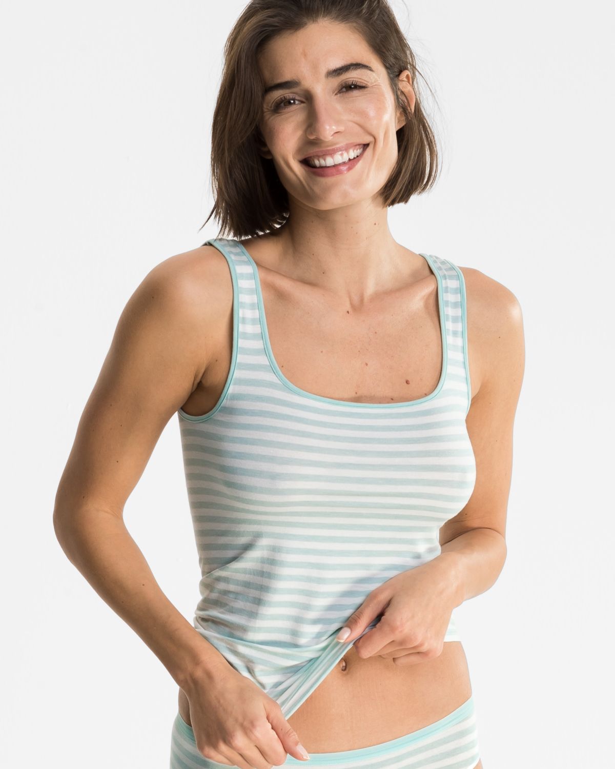 Model trägt Achselhemd in minze / off white aus der Serie Regina, Ansicht von vorne.