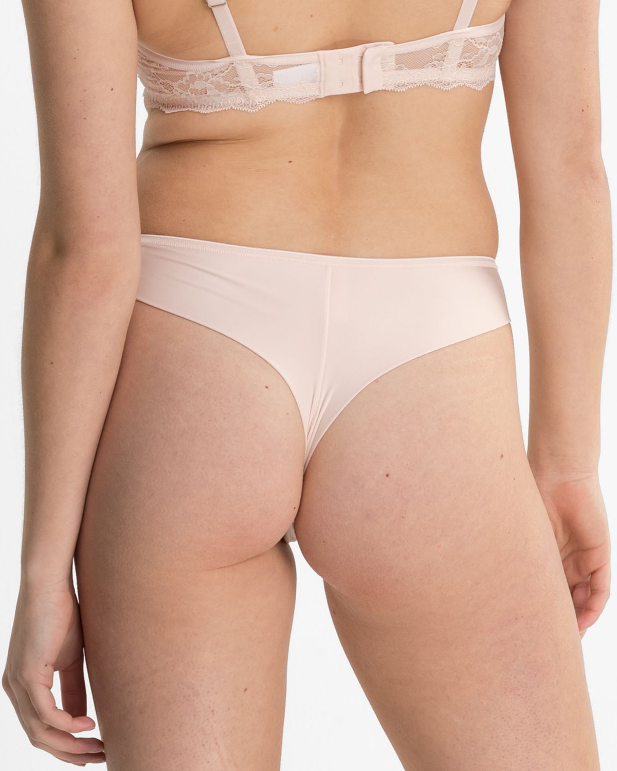 Model trägt Brazilstring in lychee aus der Serie Lacy, Ansicht von hinten.