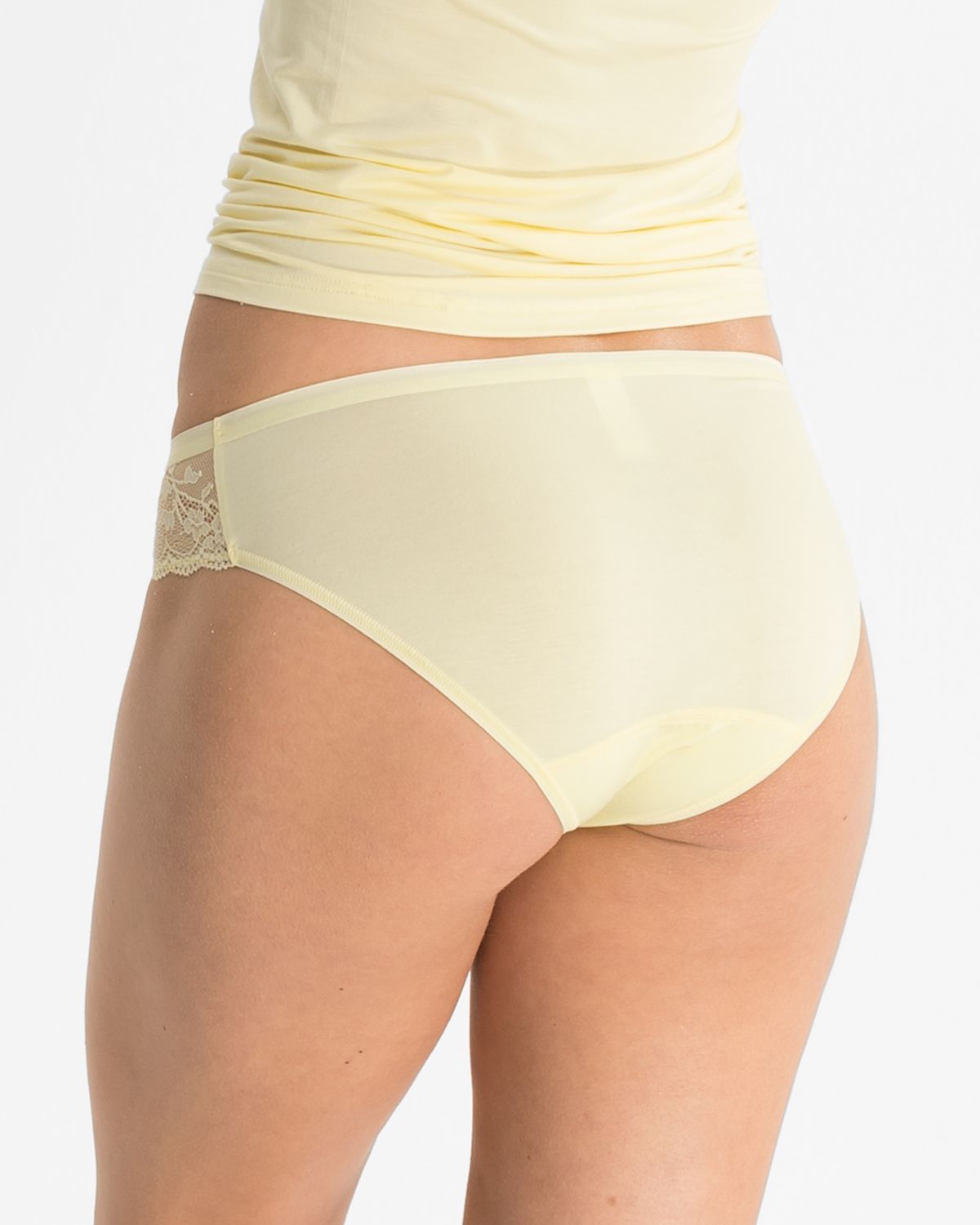 Model trägt Bikinislip in zitrone aus der Serie Romy, Ansicht von hinten.