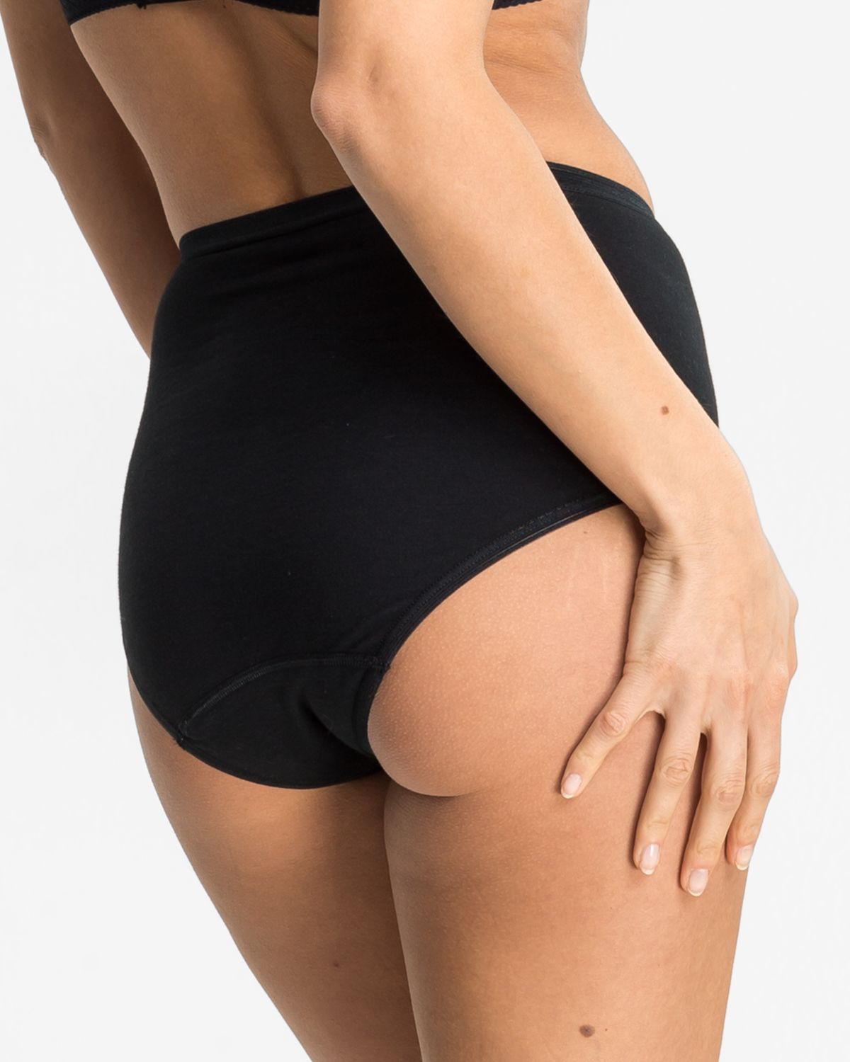 Model trägt Taillenslip in schwarz aus der Serie Britta, Ansicht von hinten.