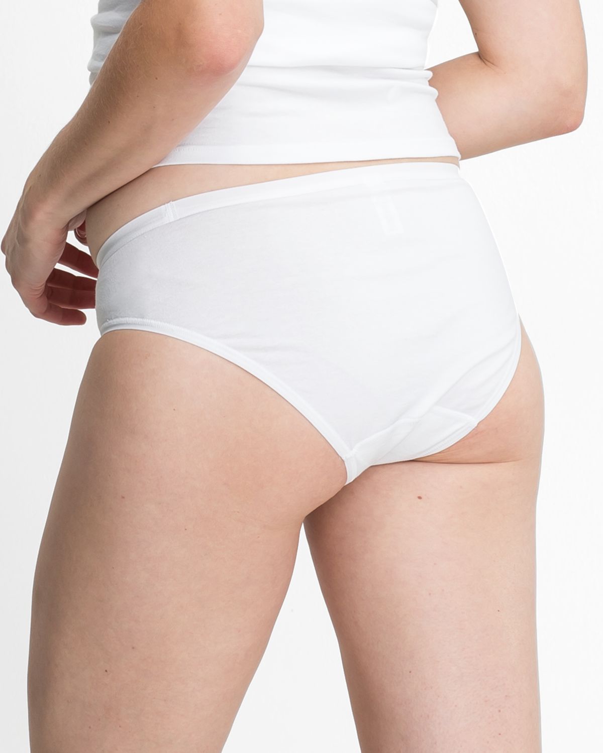 Model trägt Bikinislip in weiß aus der Serie Bio Cotton plus, Ansicht von hinten.