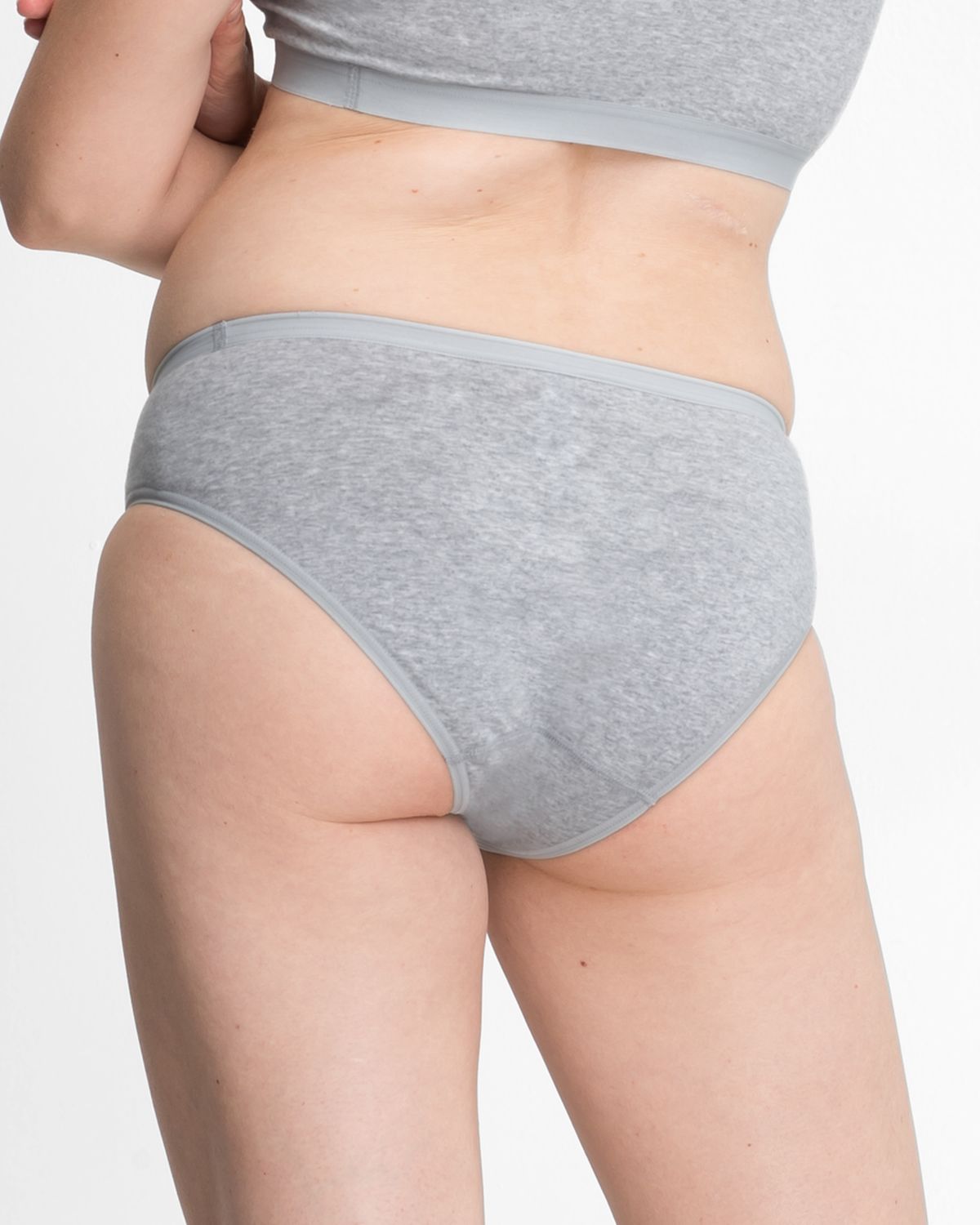 Model trägt Bikinislip in kiesel mélé aus der Serie Bio Cotton plus, Ansicht von hinten.