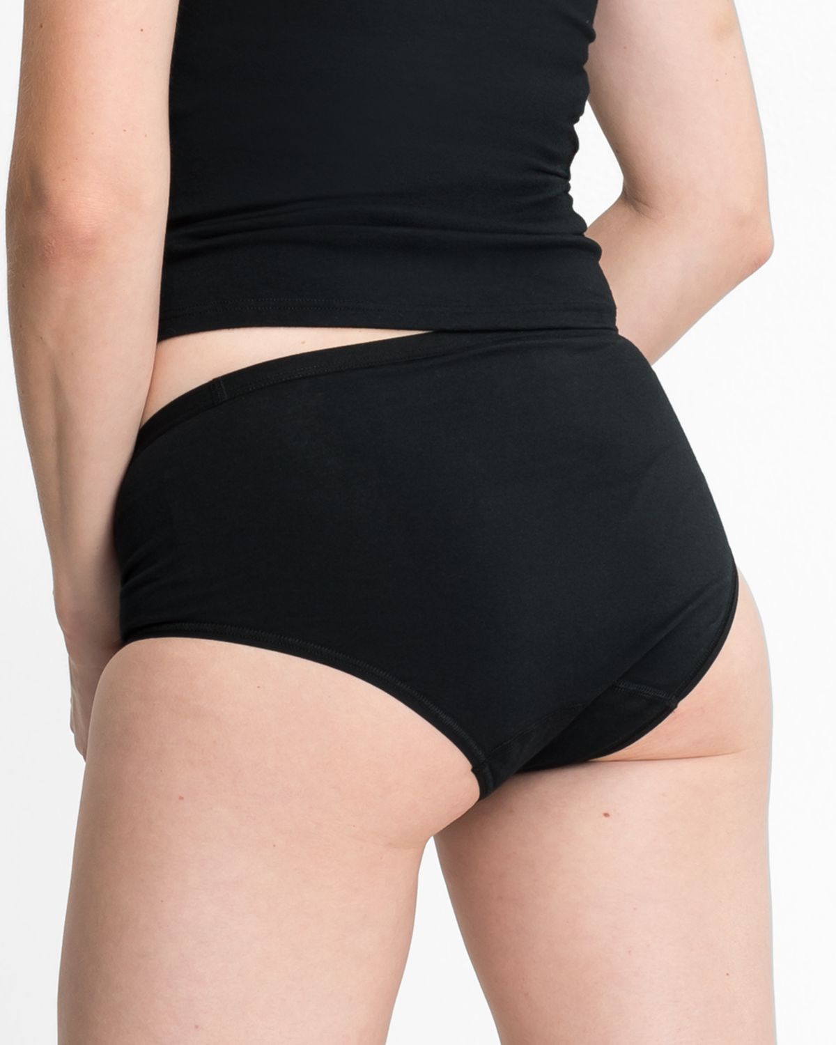 Model trägt Midislip in schwarz aus der Serie Bio Cotton plus, Ansicht von hinten.