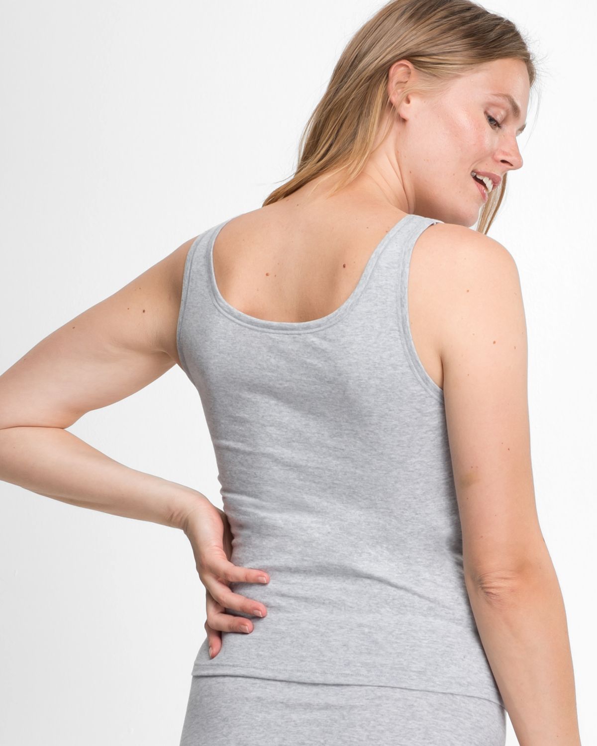 Model trägt Achselhemd in kiesel mélé aus der Serie Bio Cotton plus, Ansicht von hinten.