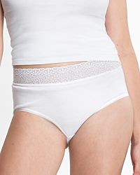 Model trägt Taillenslip in weiß aus der Serie Natalie, Ansicht von vorne.