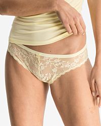 Model trägt Bikinislip in zitrone aus der Serie Romy, Ansicht von vorne.