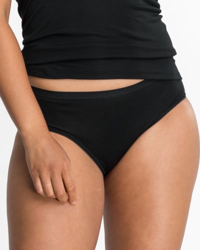 Model trägt Hüftslip in schwarz aus der Serie Nadine, Ansicht von vorne.