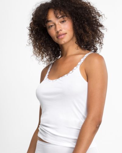 Model trägt Trägerhemd in weiß aus der Serie Nadine, Ansicht von vorne.