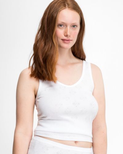 Model trägt Achselhemd in weiß aus der Serie Nora, Ansicht von vorne.